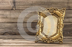 Golden baroque picture frame on wooden background