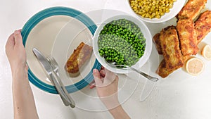 Golden batter deep fried fish fillet, served with green peas, sweet corn, and slices of lemon close up