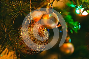 Golden bauble in Christmas tree surrounded by colorful lights