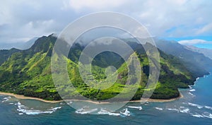 Golden beach and green mountains at the  Na Pali Coast shoreline, aerial view shot from a helicopter, Kauai, Hawaii