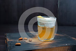 Golden beer with white foam in a beer glass is standing on a black wooden table in the bar. The drink is decorated with peanuts