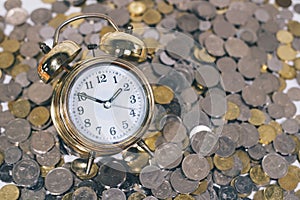 Golden bell clock on a group of coins.