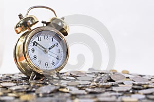 Golden bell clock on a group of coins.