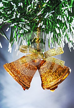 A golden bell-shaped ornament hanging on a green Christmas tree