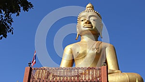 Golden big buddha with wood carving balcony and blue sky background