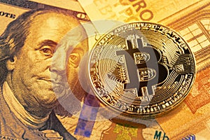 Golden bitcoin on 100 dollar and euro bills. Close up image. Cryptocurrency concept.