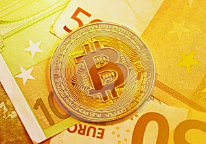 Golden bitcoin on 50 and 100 Euro banknotes background, cryptocurrency financial concept of global economic crisis. Modern income