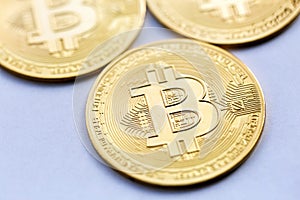 Golden Bitcoin close up, next to other coins out of focus