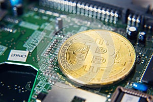 Golden bitcoin coin lying on computer motherboard, cryptocurrency mining concept