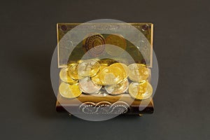 Golden bitcoin coins and banknote in the treasure trove, cryptocurrency in wooden chest, gift, decoration on black paper