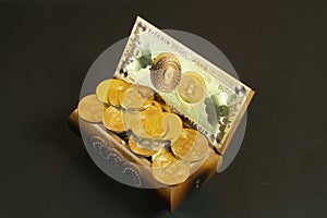 Golden bitcoin coins and banknote in the treasure trove, cryptocurrency in wooden chest, gift, decoration on black paper