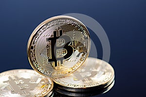 Golden bitcoin coins on a dark background with reflection. Virtual currency. Crypto currency. New virtual money.