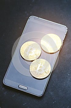 Golden bitcoin coins on a smart phone. Virtual currency. Crypto currency. New virtual money. Lens flare