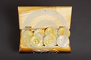 Golden bitcoin coins in the treasure trove, cryptocurrency in wooden chest, gift, decoration on black paper background