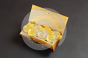 Golden bitcoin coins in the treasure trove, cryptocurrency in wooden chest, gift, decoration on black paper background