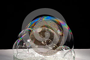 golden bitcoin crypto currency behind colorful soap bubbles bevor bursting