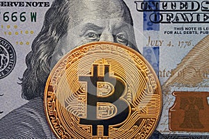 Golden bitcoin with evil, wicked Benjamin Franklin portrait from one hundred american dollars. Business concept of worldwide crypt