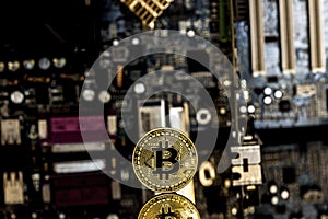 Golden bitcoin in front of a motherboard
