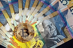 Golden Bitcoin glowing on top of Australian 50 dollar banknotes closeup.