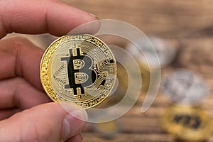 Golden Bitcoin holding in mans fingers closeup