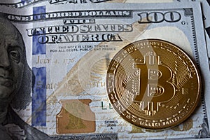 Golden bitcoin on a hundred-dollar bills.