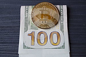 Golden bitcoin on a hundred-dollar bills.