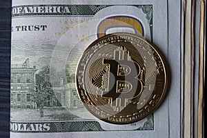 Golden bitcoin on a hundred-dollar bills.