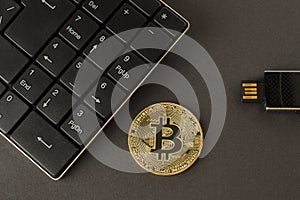 Golden bitcoin, keyboard and flash drive on a dark background top view