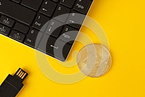 Golden bitcoin, keyboard and flash drive on a yellow background