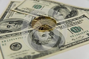 Golden bitcoin lie on one hundred dollar bills