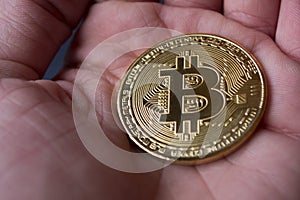 Golden bitcoin in male hand.