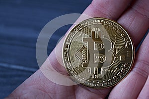 Golden bitcoin in male hand.