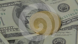 Golden bitcoin on one hundred dollar bills of dollars spinning