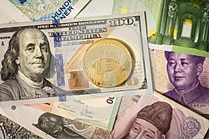 Golden bitcoin over multi currency banknotes dollar, yuan, euro