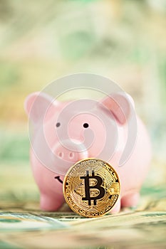 Golden bitcoin on piles of money leaning on pink piggy bank. Wealth, savings, digital, virtual, currency, and cryptocurrency