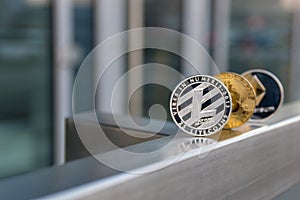 Golden bitcoin silver litecoin and ethereum on metal handrail