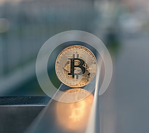 Golden bitcoin stand on metal handrail