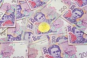 Golden bitcoin on two hundred ukrainian hryvnia bills background