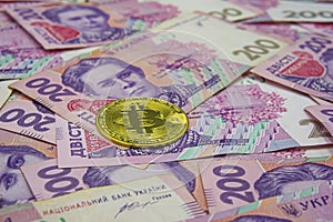 Golden bitcoin on two hundred ukrainian hryvnia bills background