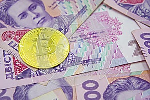 Golden bitcoin on two hundred ukrainian hryvnia bills background