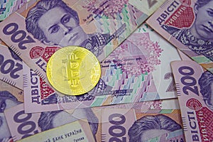 Golden bitcoin on two hundred ukrainian hryvnia bills background