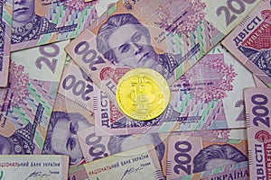 Golden bitcoin on two hundred ukrainian hryvnia bills background