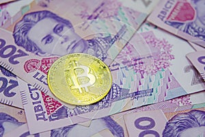 Golden bitcoin on two hundred ukrainian hryvnia bills background