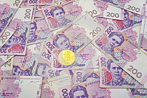 Golden bitcoin on two hundred ukrainian hryvnia bills background