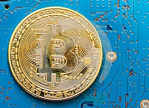 Golden Bitcoin virtual currency on a circuit board.