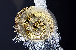 Golden bitcoin and water splash on dark background. Money laundering concept