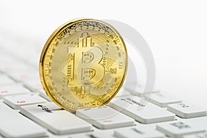 Golden Bitcoin on white keyboard