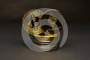 Golden bitcoinand ethereum stand on pile of coins on dark background