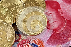 Golden bitcoins close up with a 100 yuan note