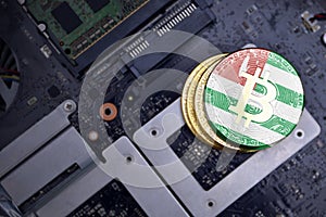 Golden bitcoins with flag of abkhazia on a computer electronic circuit board. bitcoin mining concept